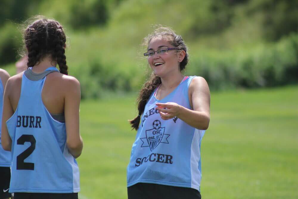 An Oneonta Soccer Club player smiles and laughs with a teammate