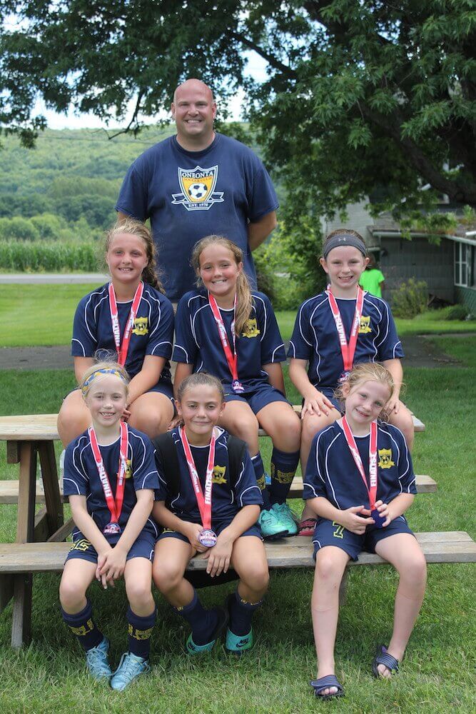 A group of teammates and their coach pose for a picture after winning second place in the tournament