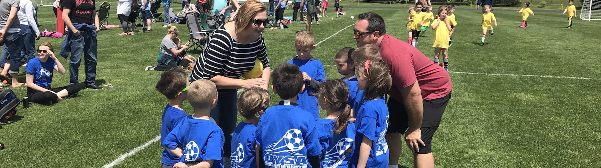 Kids huddle with a coach to discuss the next play